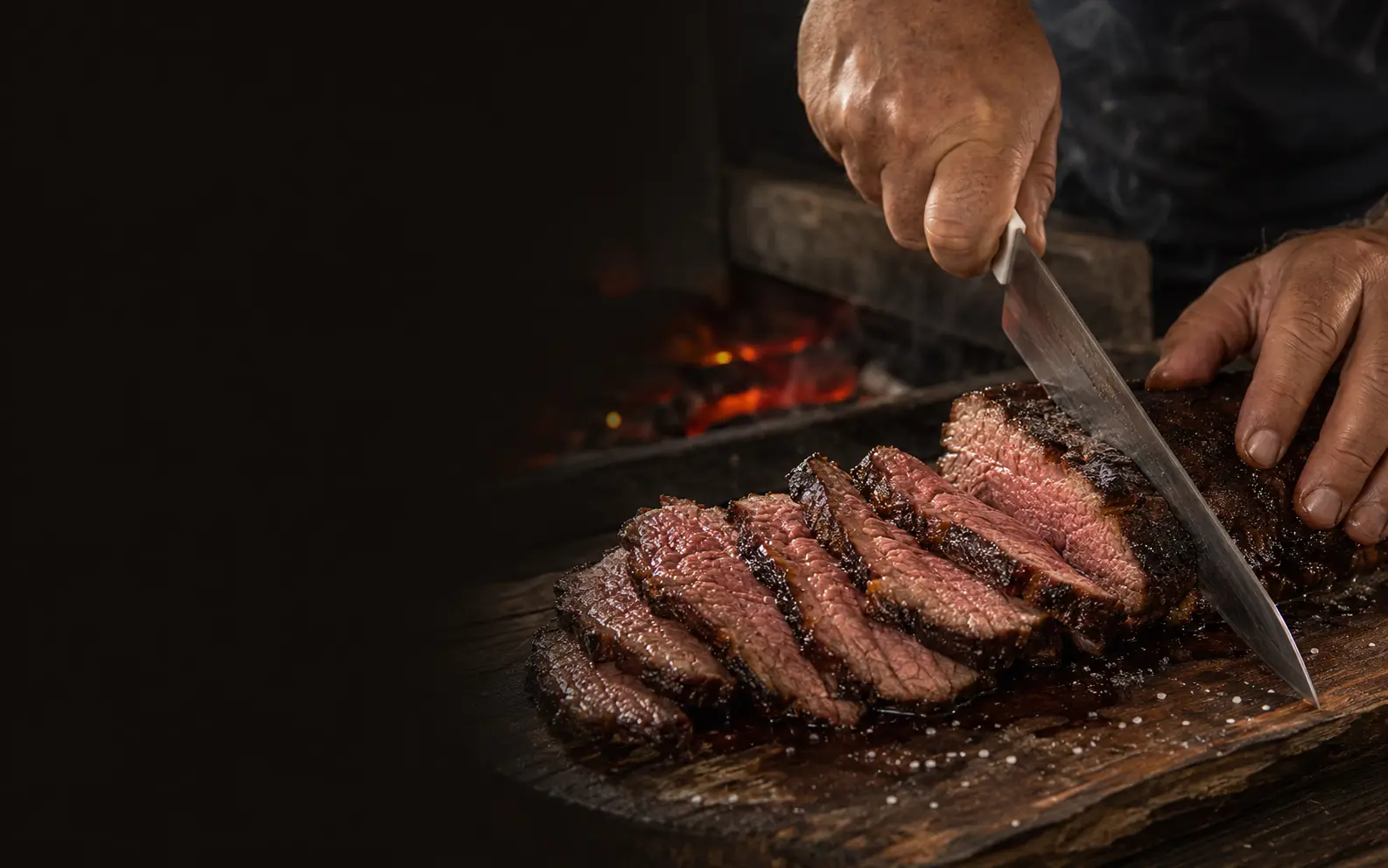 Carne suculenta sendo cortada contra as fibras sobre uma tábua